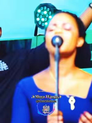 The cover image features a person singing into a microphone, positioned center-frame, with their eyes closed. They are wearing a blue dress, and the image is brightly lit. The background appears to be a stage setting with visible stage lighting at the top.