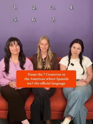 Three young women are seated on a red couch against a backdrop of a solid purple-ish wall. Above the women are numbers indicating potential answer choices. An orange banner across the middle of the image states: "Name the 7 Countries in the Americas where Spanish isn't the official language."