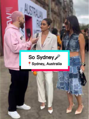 The cover image features three people standing on a city street. The person on the left is a man wearing a pink hoodie and black pants, talking into a microphone. In the middle, a woman in a white blazer and pants. On the right, a woman in a denim vest and skirt. Text overlays read 'So Sydney' indicating a location; the background includes buildings and signs.