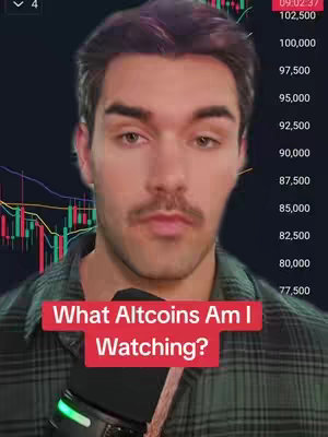 A man with dark hair and a mustache is centered in the frame, looking towards the viewer with a neutral expression. He's wearing a plaid shirt. Behind him is a chart showing trading data, with green and red bars, and values listed along the right-hand side. A text overlay reads 'What Altcoins Am I Watching?' in a red box at the bottom.