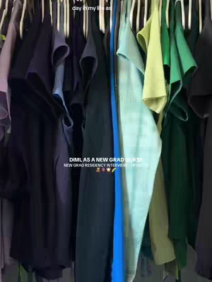 A vertical shot of a closet filled with various shades of clothes hanging on hangers. The clothes range from dark blues and blacks to lighter greens and blues. Text overlays highlight "day in my life as" and "DIML AS A NEW GRAD NURSE".