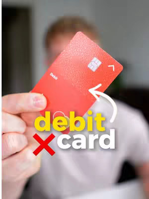 The cover image shows a person holding a red debit card with the word 'debit card' in large yellow and white text overlayed with a red 'X' in the foreground. An arrow points from the X to the card and the background is slightly out of focus.