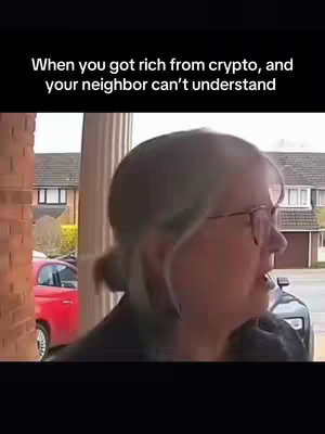 A woman with short gray hair and glasses stands in front of a brick building. Text overlayed on the image reads, 'When you got rich from crypto, and your neighbor can't understand'. A red car is visible in the background.