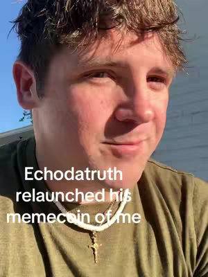 A man with light skin and short, tousled brown hair is the focus of the image. He's wearing an olive-green t-shirt and a white necklace with a gold cross pendant. Text overlayed on the image reads 'Echodatruth relaunched his memecoin of me'. The background is a softly lit, blurred outdoor setting. The man is smiling and looking slightly off-camera.
