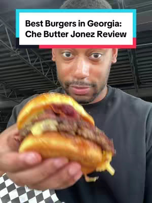 A man holds a burger in front of his face, with a text overlay at the top. The burger has a sesame seed bun and the man is looking at the camera.