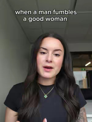 A woman with long dark hair facing the camera making a speech. There is text overlayed at the top that reads, "when a man fumbles a good woman". She is wearing a black top and a necklace with a green stone pendant.