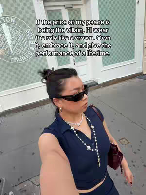 A selfie-style shot of a woman in sunglasses and dark clothing walking on a city street. The background reveals what appears to be a high-end retail storefront. Text is overlaid on the image, using a sans-serif font.