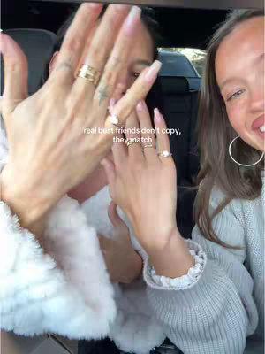 The cover image shows two people's hands with long nails in front of the camera. The text is layered on top of the image, and the women are in what appears to be a car. One of the people is wearing a white coat, and the other is wearing a white top. One has a ring on their ring finger and the quote in the image says, "real best friends don't copy, they match".