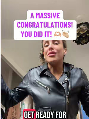The image is a selfie-style shot of a woman wearing a black leather jacket. She's positioned against a blurred background, likely indoors, with warm lighting that highlights her face. The jacket has visible zippers and a classic biker style. Overlaying her is a white box with purple text that reads, "A MASSIVE CONGRATULATIONS! YOU DID IT!" with heart and clapping hands emojis.