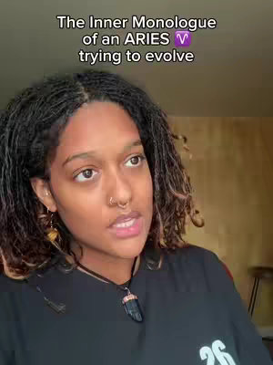 A medium close-up shot features a young woman with dark skin and locs, looking slightly upward and to the side as if in thought. She wears a black shirt and a necklace. Text overlays in the top center of the image reading: 'The Inner Monologue of an ARIES trying to evolve'. The background is blurred.