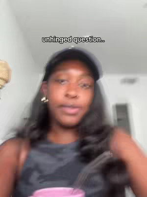 A dark-skinned woman wearing a black cap and a gray top is positioned in front of an out-of-focus background. The image is slightly blurred, suggesting motion or a shallow depth of field. Text overlay in a black simple font appears at the top. The woman appears to be speaking.