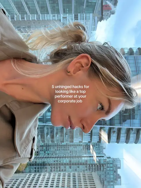 A woman's profile is captured in a selfie style photo. She is looking down and to the left with skyscrapers filling the window behind her. The text overlay reads, "5 unhinged hacks for looking like a top performer at your corporate job."