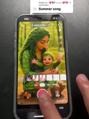 A photo of a phone screen showcasing an AI-generated image of a woman holding a baby. Both are clad in green, with foliage-like textures. The smartphone is held by a person, with a thumb touching the screen, interacting with a video recording app.