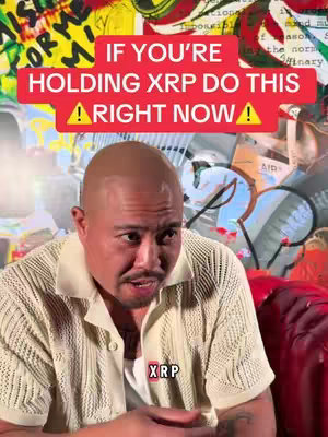 A man with a shaved head and a light-colored collared shirt is speaking. A red rectangular text overlay states, "IF YOU'RE HOLDING XRP DO THIS RIGHT NOW!" with an exclamation point after each word; a large colorful patterned background is behind him and an XRP text graphic.