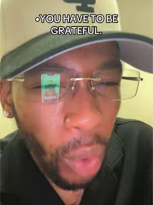 A selfie-style shot of a man with glasses and a baseball cap on, lit from the front. The man's face takes up most of the image, with text overlaying which reads, '.YOU HAVE TO BE GRATEFUL.'