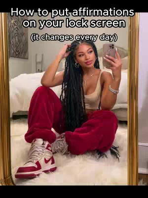The cover image features a young woman sitting in front of a mirror, holding a phone, reflecting a bedroom setting. She wears a beige top and red sweatpants, paired with white and red sneakers. The composition is framed by a gold-colored mirror, with text on top, the woman has long black braids and is wearing a hoop earring.