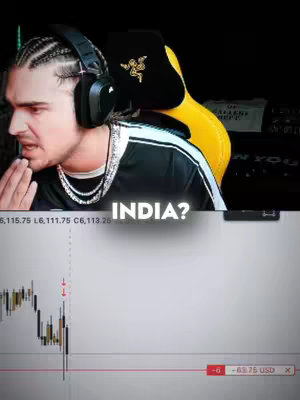 A man with braids, a diamond necklace, and headphones is shown in a close-up. Below him is a chart with red and green lines. The text overlay asks "INDIA?".