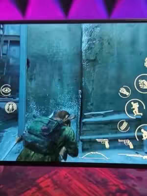 A screenshot of a mobile game interface, displaying a character aiming a weapon in a dimly lit, blue-toned environment. On-screen buttons and UI elements for gameplay are visible.