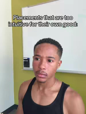 A medium shot features a young man in a black tank top, standing in front of a whiteboard. The background is a light green wall. Text overlay above the man's head reads, 'Placements that are too intuitive for their own good:'