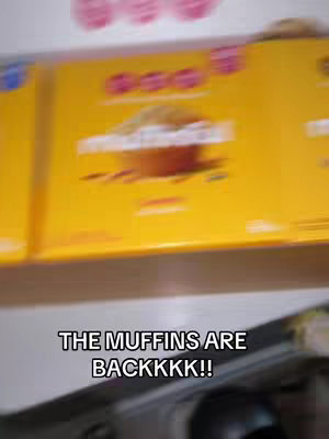The cover image shows a slightly blurry shot of a shelf filled with boxes of muffins. The boxes are primarily yellow with orange accents. Text overlay at the bottom reads "THE MUFFINS ARE BACKKKK!!".