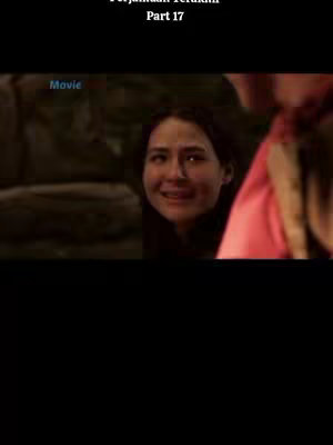 A close up shot from a movie the frame is focused on the face of a woman with a slight smile. She appears to be amidst a dark outdoor setting, possibly a forest.
