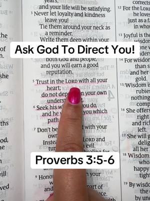 A vertical shot shows an open book with text. A finger is placed on the highlighted text “Trust in the LORD with all your heart.” Two white rectangular text overlays are positioned on top of the book. One says, “Ask God To Direct You!” The other, positioned below, “Proverbs 3:5-6”. The finger has pink nail polish.