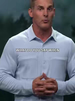 A man in a light blue button-down shirt stands in front of a blurred background of trees. Text overlay at the center reads 'WHAT DO YOU SAY WHEN'.