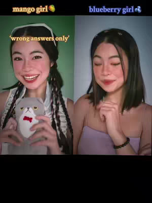 Cover image is a split screen, with the creator as 'mango girl' on the left, holding a stuffed cat toy and smiling, and as 'blueberry girl' on the right, with a hand near chin in a more pensive pose. Text overlays specify their 'roles', and the hook is 'wrong answers only'.
