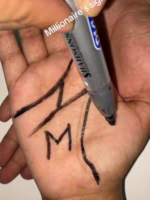 A hand with visible palm lines is being drawn on with a black marker, forming the letter 'M' and two lines along the palm's creases. The hook says 'Millionaire's sign'.