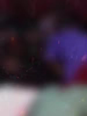 The image is a blurry composite of dark and light colors, lacking clear focus or distinct details. The predominant color appears to be a deep purplish-black, which seems to blend into gradients of lighter hues near the lower portion.