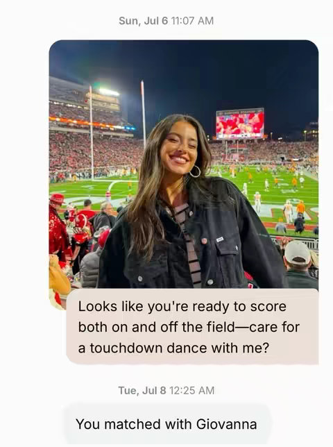 The image shows a woman smiling brightly at a football stadium, overlaid with a text bubble containing a dating-related message. The woman is positioned with the football field and stadium crowd in the background, suggesting a lively, outdoor setting. The lighting appears to be nighttime. The text bubble is stylized to resemble a text message conversation.
