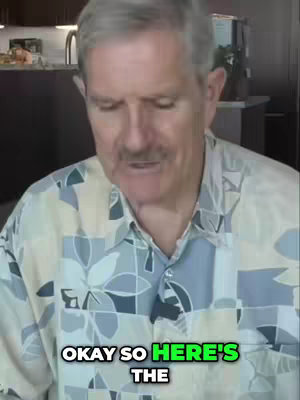 A middle-aged man with gray hair and a mustache is speaking, his body partially visible. He wears a patterned button-down shirt. The text overlay at the bottom of the image reads 'OKAY SO HERE'S THE' in a bold, white font with a green outline.