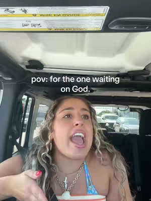The cover image shows a young woman inside a vehicle, likely a car or SUV, with her head and shoulders visible. She has long, wavy blonde hair and is wearing a blue and white patterned top. Her mouth is wide open as though she's shouting or singing. The background indicates she is driving, with a view of other cars and road elements visible through the windshield. Overlaying the image is white text, positioned centrally in the upper portion of the screen.
