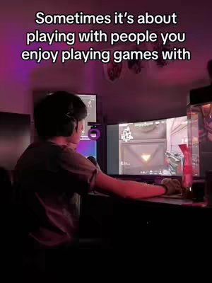 A person is sitting in a darkened room with multiple computer monitors showing a video game. Text overlays the image with a message about playing games with friends.