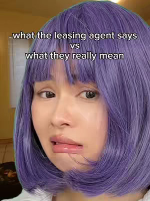 A close-up shot of a person with purple hair and a distressed facial expression, against a blurred yellow background. Text overlay reads "what the leasing agent says vs what they really mean".
