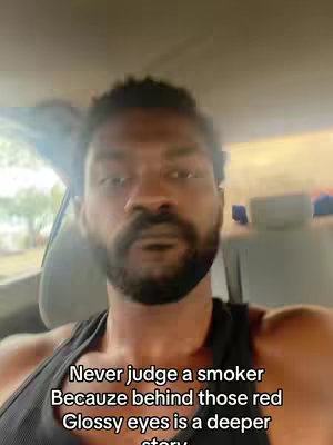 Image shows a close-up of a Black man in a car. Text overlay: "Never judge a smoker Because behind those red Glossy eyes is a deeper story."