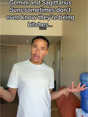 A man with brown skin stands in front of a bland background with text overlays at the top, his arms spread out in a questioning gesture. He is wearing a white t-shirt and has a surprised expression on his face.