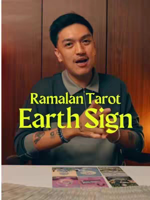 A man in a gray crew neck sweater is the central focus, set against a warm, brown background. The man has dark hair, and he is looking directly at the viewer with a slight smile. Positioned just below are several tarot cards. Overlaid on the man is a yellow text overlay reading "Ramalan Tarot Earth Sign".