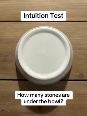 The image shows a top-down view of a white bowl on a wooden surface. Two text boxes are added as hooks; one says "Intuition Test", and the other asks how many stones are under the bowl.