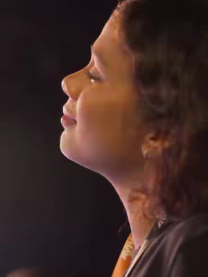 The cover image presents a close-up shot of a woman from a side profile, set against a dark background. Her face is slightly angled upwards, suggesting a moment of introspection or prayer. Her eyes are closed, and her lips are gently parted, revealing a sense of peace. Soft lighting highlights her features, and a hint of an orange lanyard can be seen around her neck. The overall composition emphasizes serenity and emotional depth.