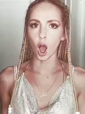 The cover image features a woman with long, braided hair, wearing a stylish top and a necklace. She has a surprised expression with her mouth open, and the background appears to be a light-colored wall.