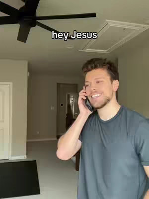 A man is on a phone call, indoors. The hook, "hey Jesus" is overlaid on the image. The man is smiling while holding his phone to his ear. The background includes a ceiling and an open door.