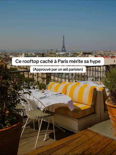 The cover image features a rooftop restaurant setting with a view of Paris, including the Eiffel Tower in the background. A table is set with white tablecloths, glasses, and silverware. The seating includes yellow and white striped cushioned benches. Text overlays in a white box state, "This rooftop hidden in Paris deserves its hype (Approved by a Parisian eye)". The sky is blue, indicating a clear day. The overall composition focuses on the dining experience with a view.