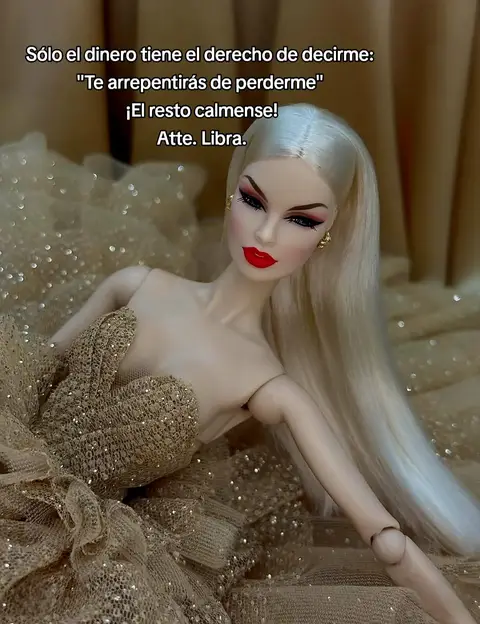 The image features a doll with long blonde hair and full glam makeup, including red lipstick and dramatic eye makeup. The doll is wearing a gold, glittery dress and posing with a slight recline. Text in Spanish is written on top.