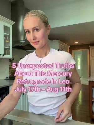 A woman in a white t-shirt stands in a kitchen setting, looking towards the camera with a soft smile. Text overlaid indicates the topic is about Mercury retrograde in Leo. The background shows kitchen cabinetry and a stainless-steel range hood.