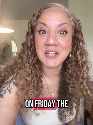 A woman with long, wavy, gray-streaked brown hair and a light complexion is centered in the frame, looking directly at the viewer. She's smiling with her mouth slightly open, and wearing makeup. The text overlay reads 'ON FRIDAY THE' on a pink rectangle.