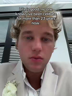 A man with light skin is centered in the frame, slightly angled towards the camera. He has blond, wavy hair, and is wearing a light-colored suit jacket with a white shirt underneath. A small, white floral accessory is pinned to his lapel. The background has vertical blinds. Overlaying the image at the top is text in a white, sans-serif font.