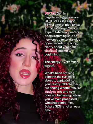 A selfie-style video cover image featuring a woman with curly red hair, pink eyeshadow, and red lipstick. The woman is centered in the frame, looking directly at the camera with her mouth slightly open. The background appears blurred, with dark green foliage and subtle peach-colored flower-like shapes. Text is overlaid on the image in a vertical column, utilizing a white font with a slight drop shadow for visibility.