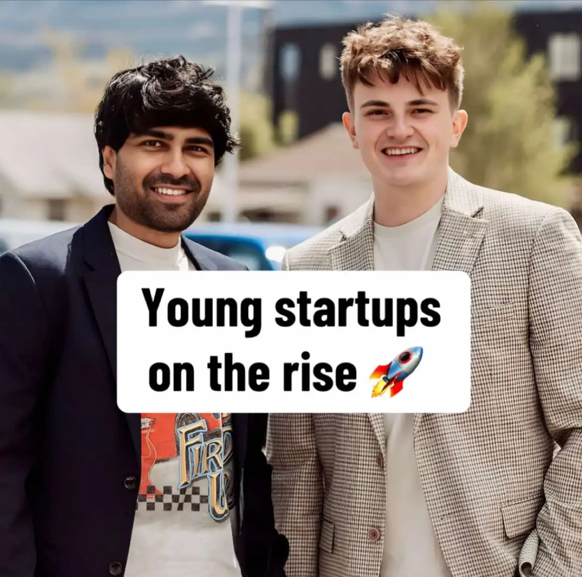Two young men in business attire are standing side-by-side, smiling at the camera. The man on the left is wearing a t-shirt with a design under a dark blazer, while the man on the right is sporting a patterned blazer. A white rectangle with the text 'Young startups on the rise' and a rocket ship icon is overlaid on them. The background appears to be outdoors with a blurred backdrop.