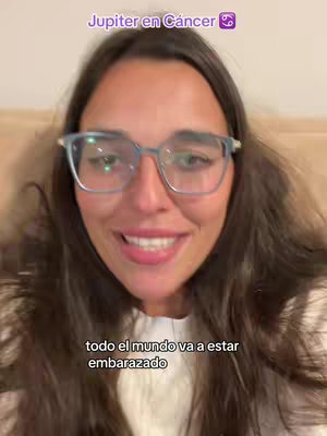 A woman with long brown hair and glasses is centered in the frame, framed against a neutral background. Two lines of white text are displayed below her.